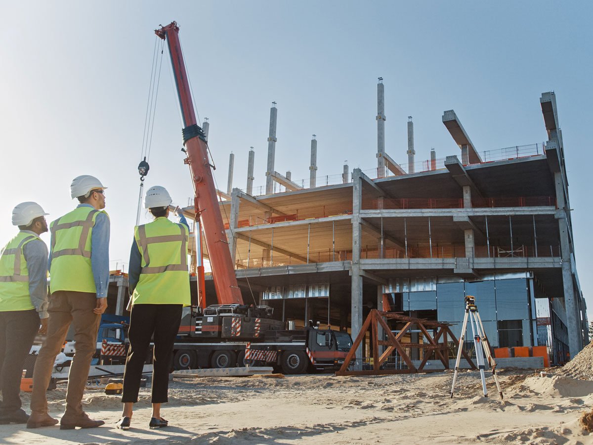 three construction workers observe commercial real estate build